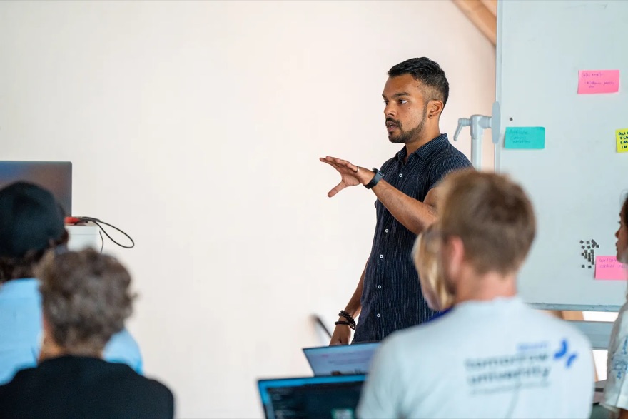 Ryan Seeras presenting at a whiteboard to a seated group