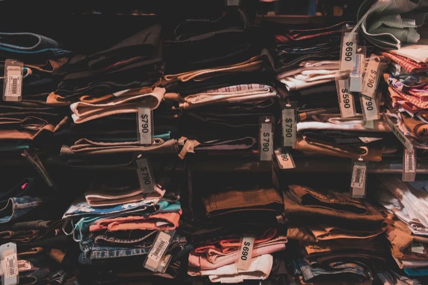 Stacks of folded clothes with price tags in a store