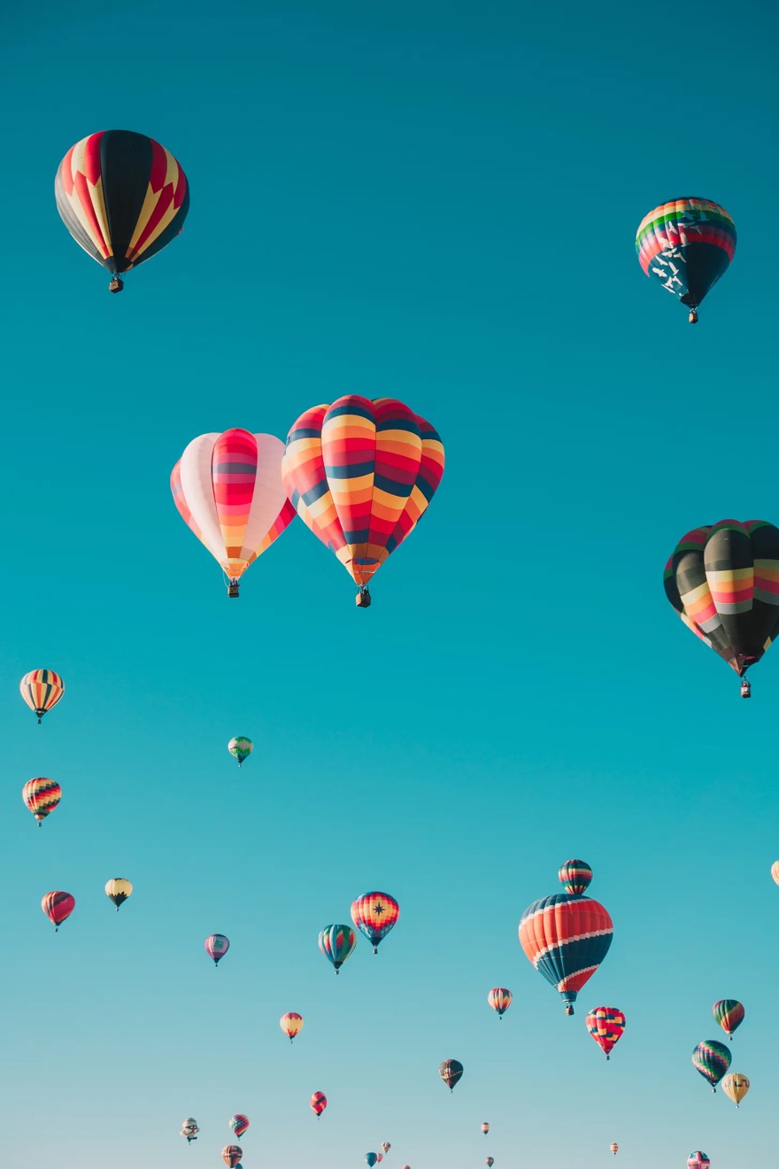 Hot air balloons rising against a clear blue sky